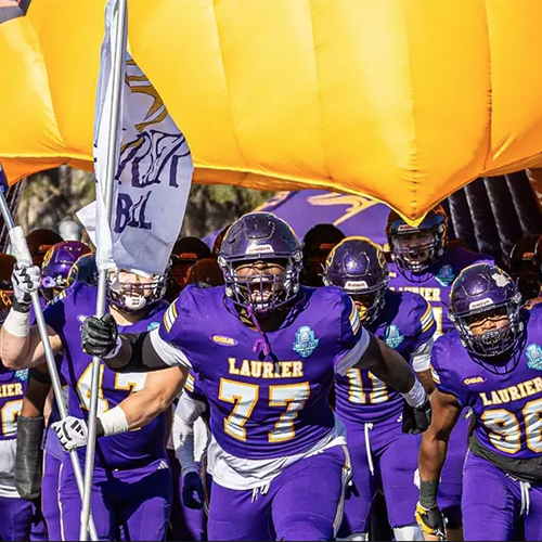 Laurier football team cheering and running onto field