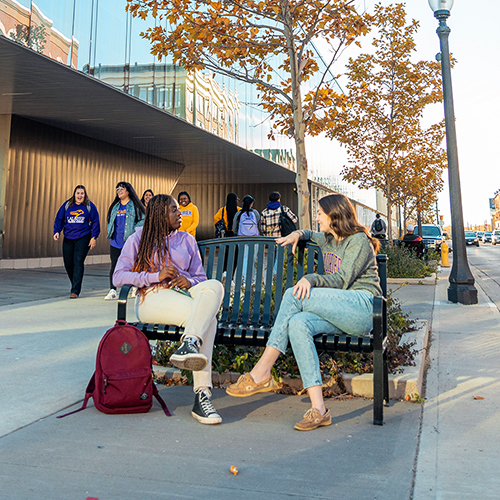 Two students sitting on a bench outside of the Brantford YMCA