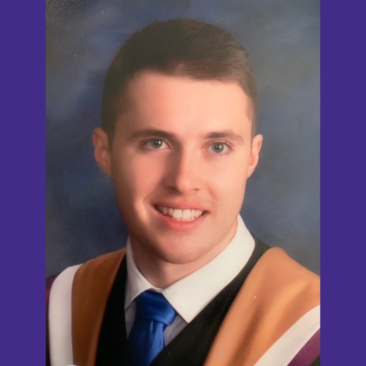 Graduation portrait of Braden Story smiling at the camera and wearing Laurier convocation robes