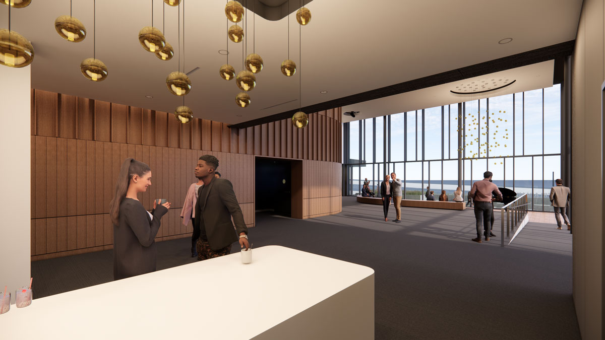 The bar area of the Savvas Chamberlain Family Foundation Lobby, a white counter and gold, globular hanging lamps, a man and a woman are talking, a light wood wall in the background, a wall of windows to the far right. People are pictured throughout the image.