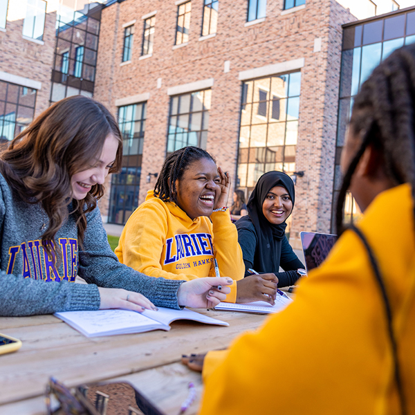 Four Laurier students studying at an outdoor picnic table.