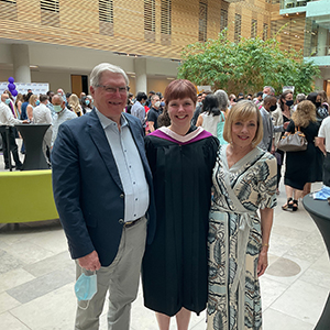 Sarah Stapleton, wearing a Laurier convocation robe, poses with her grandparents
