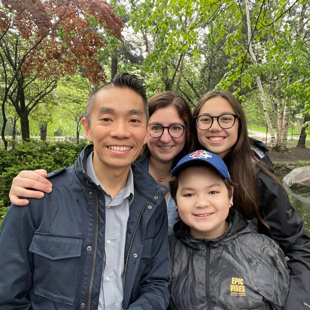 Stewart and Erin Wong grin at the camera along with their two children Clara and Charlie in an outdoor setting. 