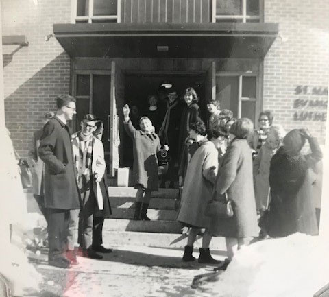 A group of young people in front of a church, some of them dancing.