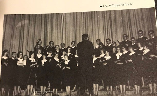 A choir singing in front of a curtain with the conductor standing in front