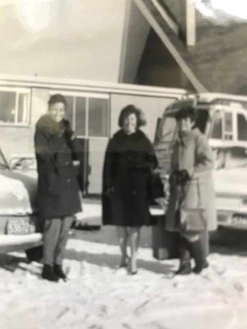 A blurry photo of three young women, standing in front of a bus.