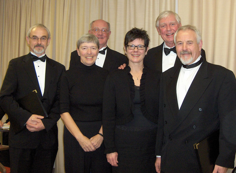 Six people wearing formal wear posed in front of a curtain.